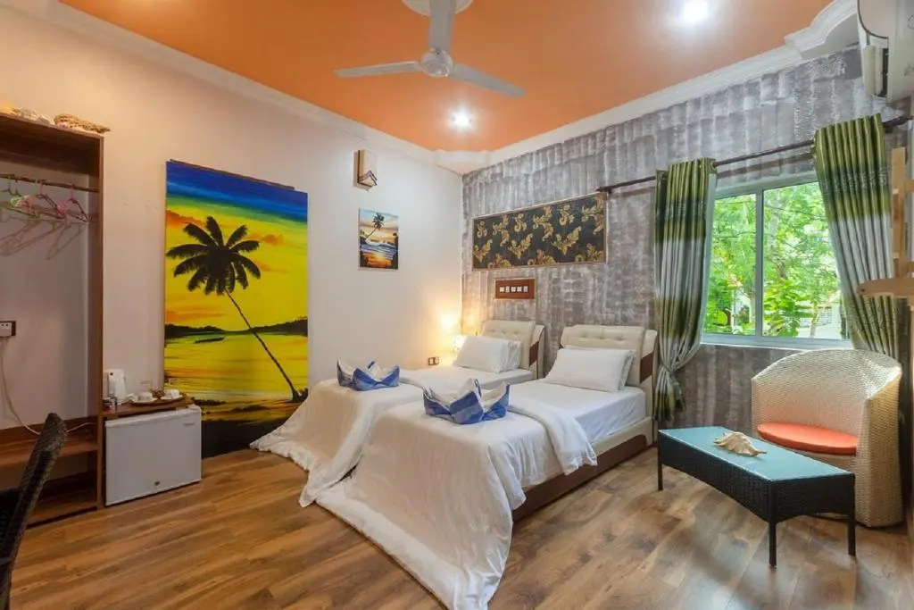 Guest room with twin beds and tropical wall art at Coral Queen Villa, Ukulhas Island, Maldives