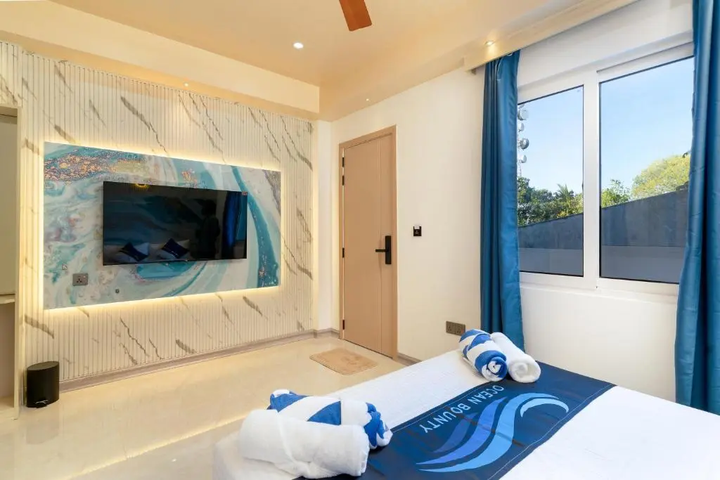 Guest room with feature wall and wall-mounted TV at Ocean Bounty, Ukulhas Island, Maldives