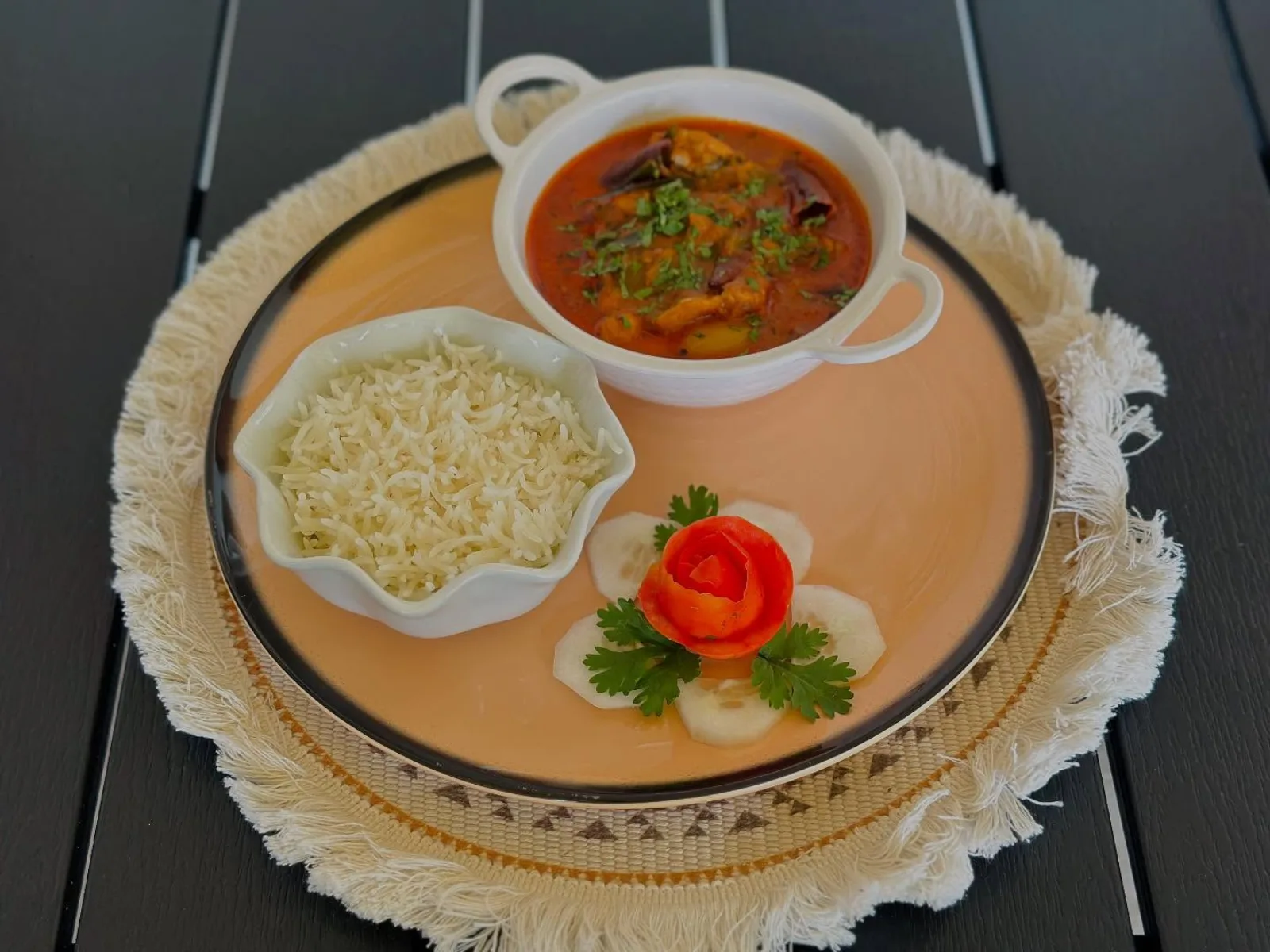 Plated curry with basmati rice and a carved tomato garnish on a dark table at Ona-Noa, Ukulhas Island, Maldives