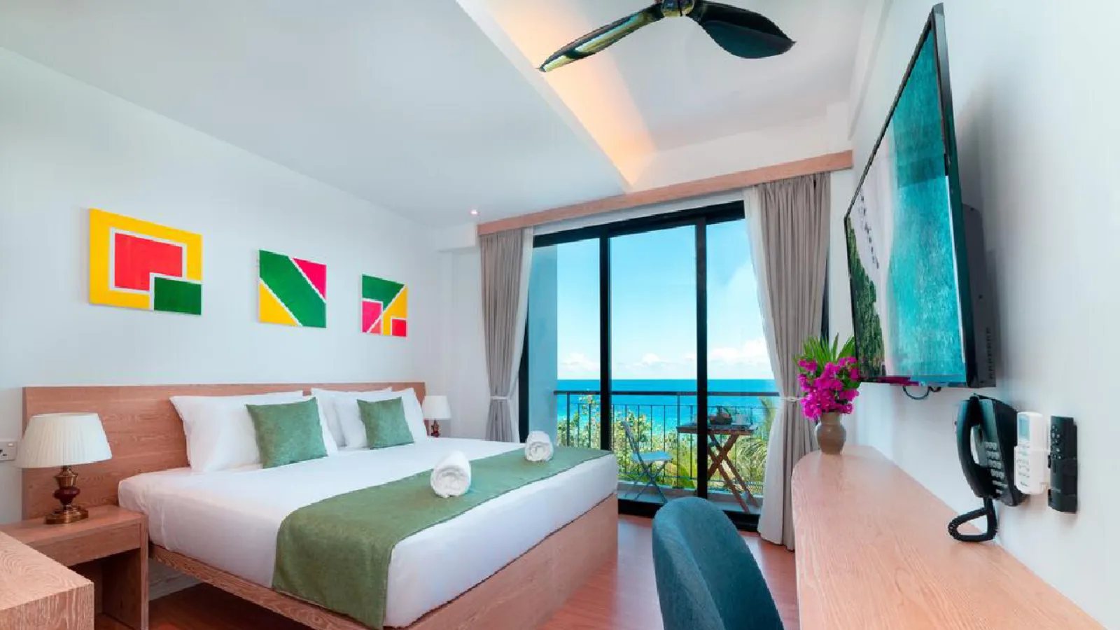 Double room with a balcony and sea view through the palms at Ranthari Hotel & Spa, Ukulhas Island, Maldives