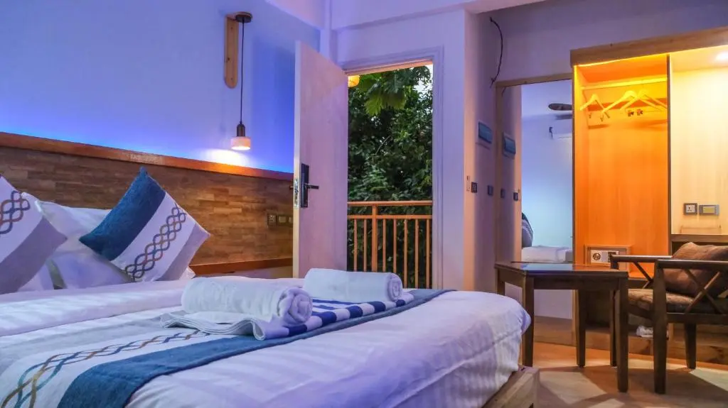 Guest room with double bed and ambient evening lighting at Rivethi Veyli, Ukulhas Island, Maldives