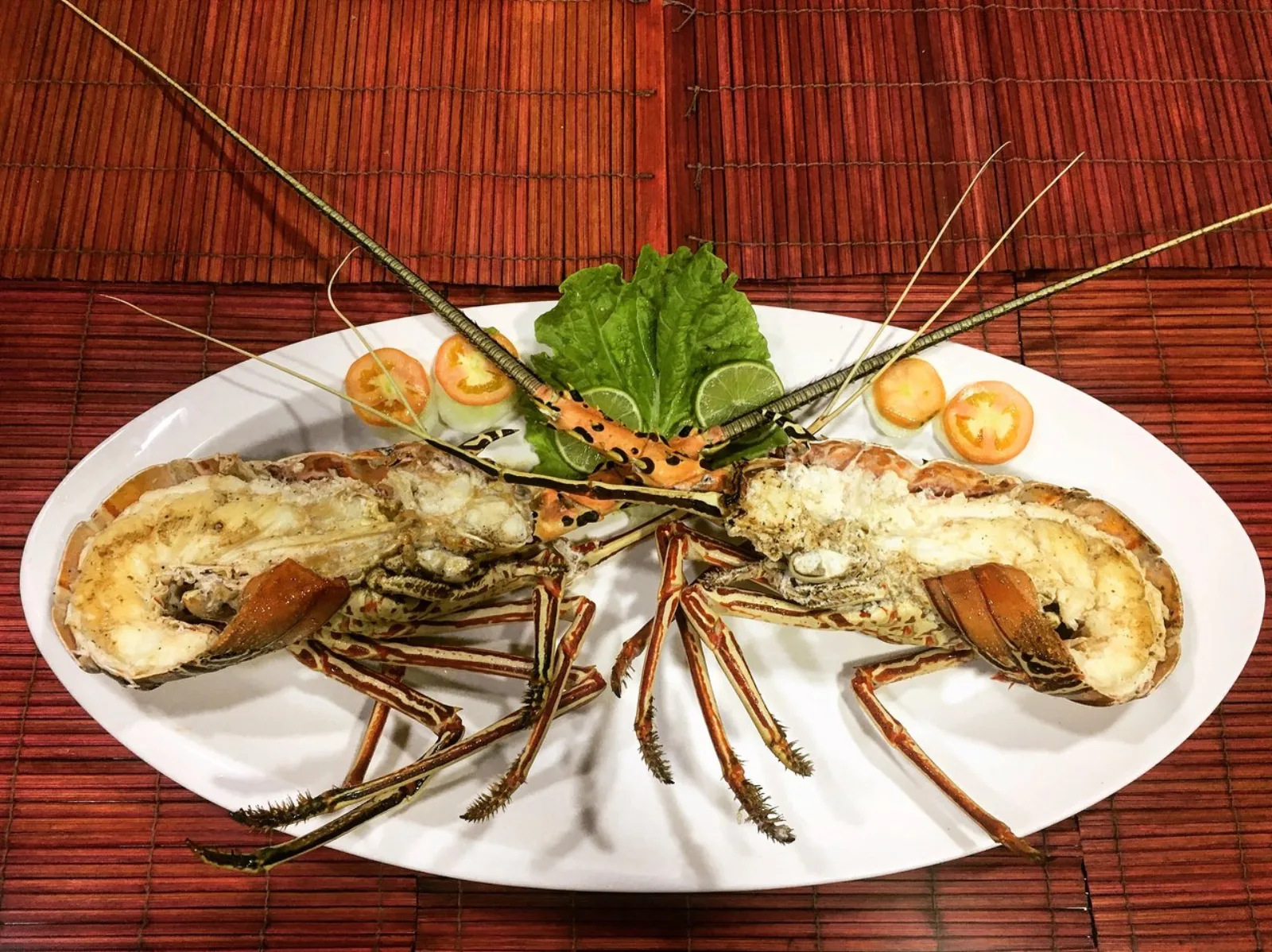 A grilled lobster platter garnished with salad, lime and tomato at Sea Salt Restaurant, Ukulhas Island, Maldives
