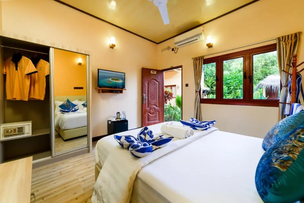 Guest room with warm wood panelling and blue accents at Sea View Villa, Ukulhas Island, Maldives