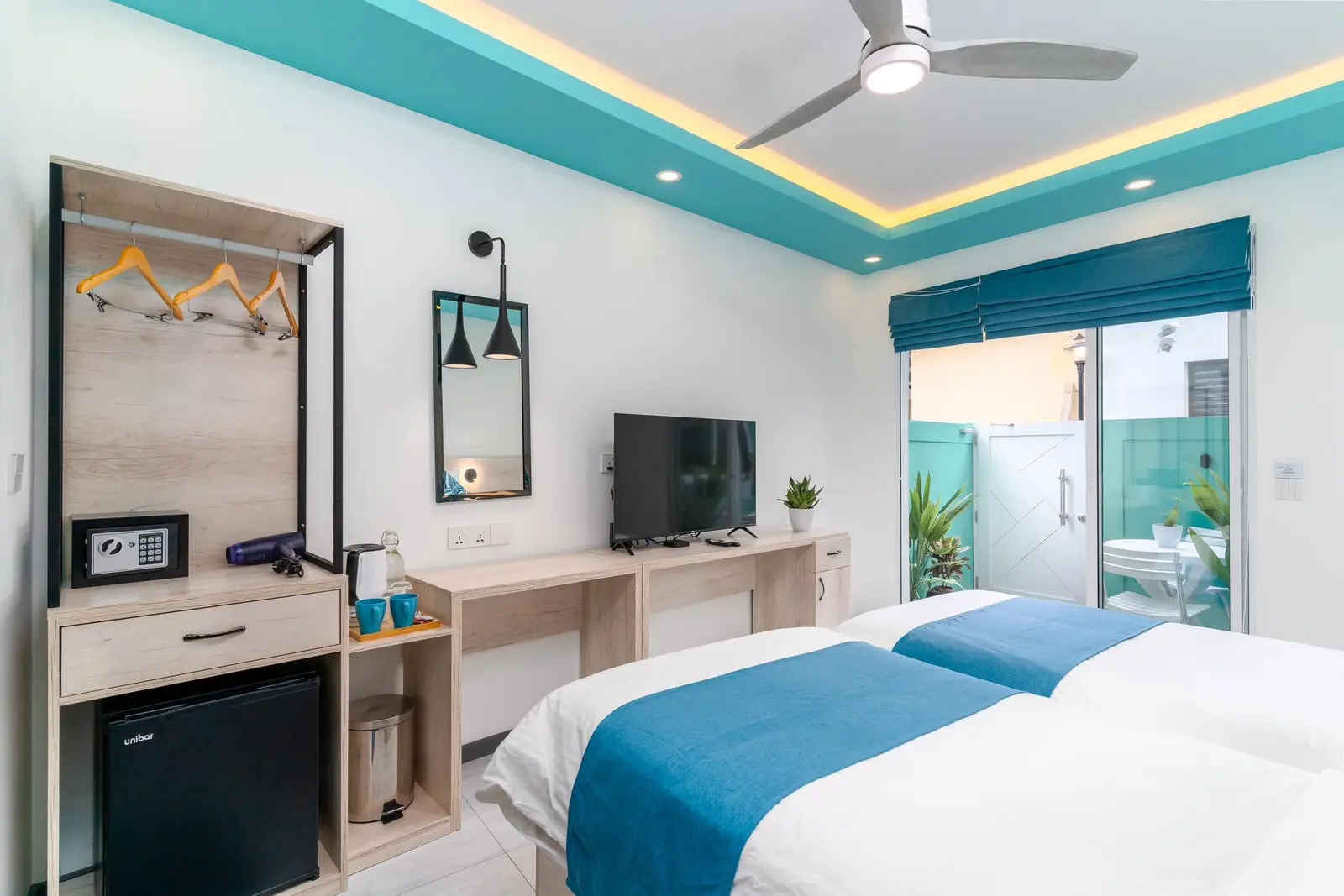 Guest room with teal accents, TV and dressing area at Ukulhas Sands, Ukulhas Island, Maldives