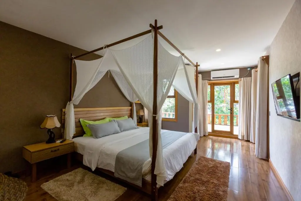 Guest room with four-poster canopy bed at West Sands, Ukulhas Island, Maldives
